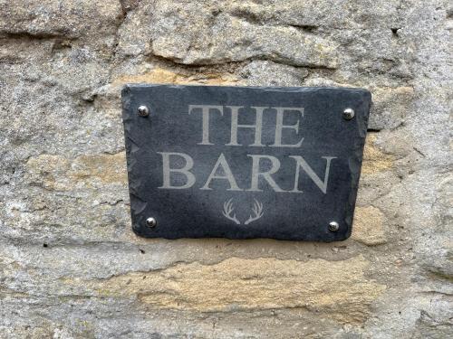 a sign that says the barn on a stone wall at The Barn in South Witham
