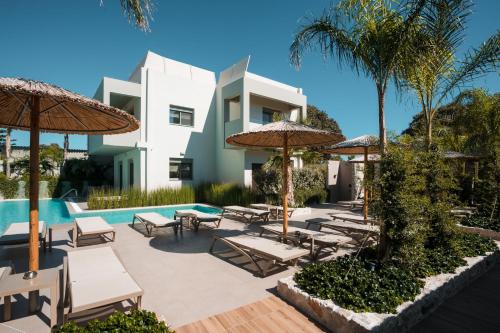 a resort with a pool and chairs and umbrellas at Sun City Luxury Apartments in Asgourou