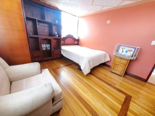 a living room with a bed and a tv in it at Suite Hostal El Trébol 2 habitaciones in Latacunga