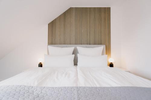 a white bed with white sheets and pillows at Küsten Suite de See - Suite 2 direkte Deichlage, Balkon, 77qm in Greetsiel