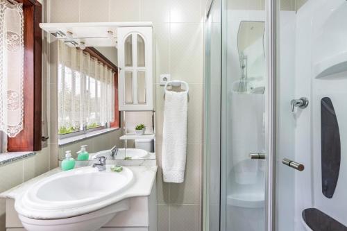 a white bathroom with a sink and a shower at Casa T1 Área Metropolitana do Porto in Carregosa