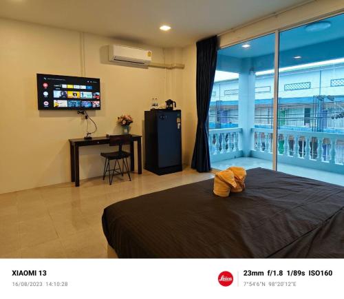 a bedroom with a bed and a desk and a television at AB House in Ban Thung Thong