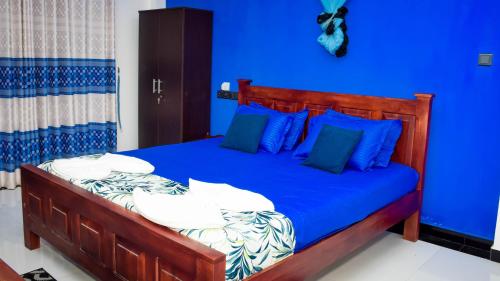 een blauwe slaapkamer met een bed met blauwe lakens en kussens bij Yala Grand Homestay in Tissamaharama
