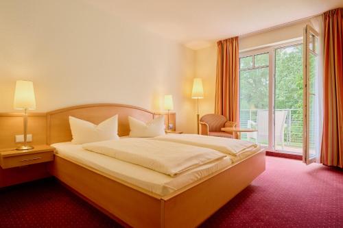 a bedroom with a large bed and a large window at Waldhotel Forsthaus Hainholz in Pritzwalk