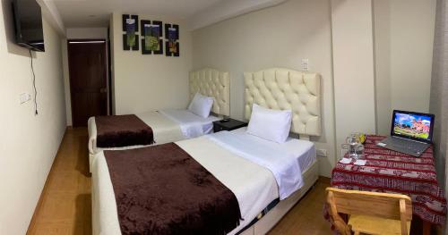 a bedroom with two beds and a laptop on a desk at ANDEAN VALLEY HOTEL in Cusco