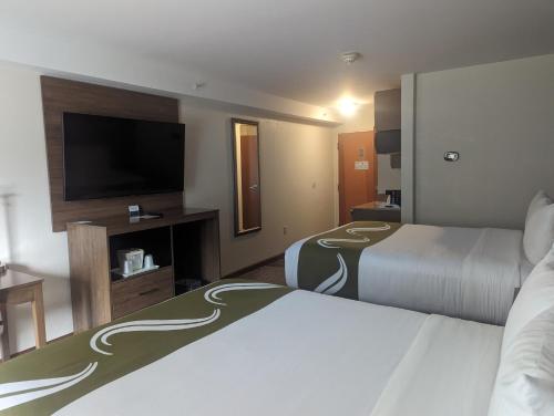 a hotel room with two beds and a flat screen tv at Quality Inn & Suites Northampton - Amherst in Northampton
