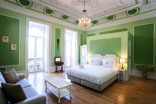 a bedroom with green walls and a bed and a couch at Casa do Principe in Lisbon