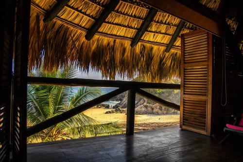 a view of the beach from a straw hut at El Alquimista Yoga Spa in Zipolite