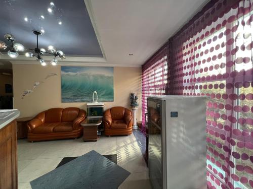 un soggiorno con 2 sedie in pelle e una TV di Three Dolphins Hotel ad Aqtau