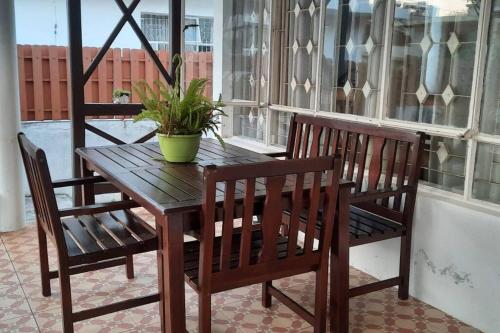 a wooden table with two chairs and a potted plant on a porch at Chez Hedley Résidence : Couple/Business in Pointe aux Sable