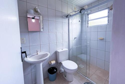 a bathroom with a toilet and a sink and a shower at Pousada Águas do Embaú in Guarda do Embaú