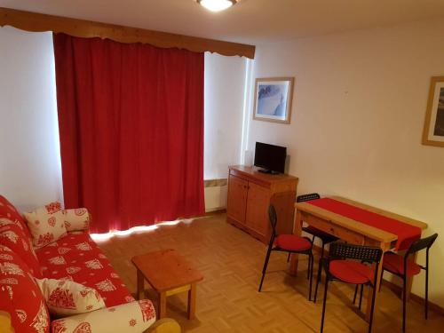 uma sala de estar com um sofá e uma mesa com uma cortina vermelha em Le studio 1800 aux pieds des pistes em Puy-Saint-Vincent