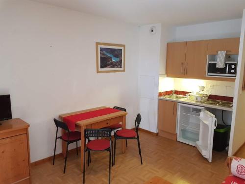 uma pequena cozinha com uma pequena mesa e cadeiras em Le studio 1800 aux pieds des pistes em Puy-Saint-Vincent