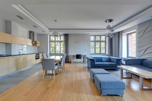 a living room with blue couches and a kitchen at Dom & House Apartments - Old Town Tobiasz Residence - Fitness & Parking in Gdańsk