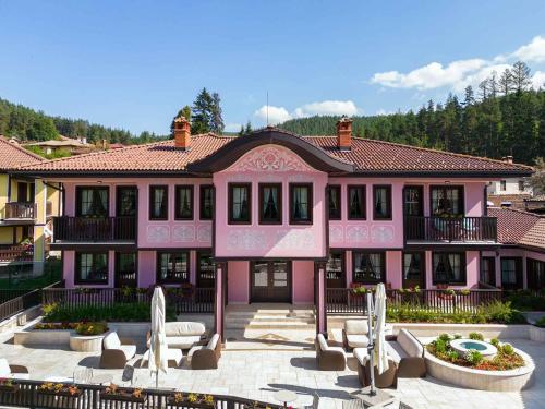een roze gebouw met stoelen ervoor bij Armaco Residence in Koprivshtitsa