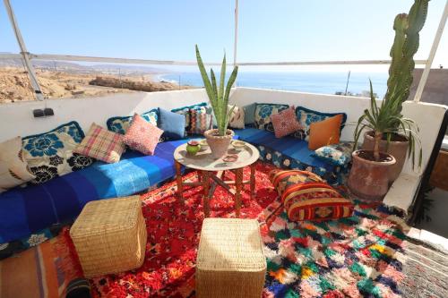 a room with a couch with pillows and a table at Welle Surf Morocco in Taghazout