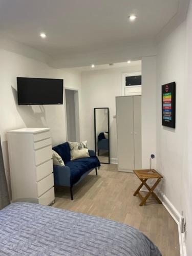 a bedroom with a bed and a chair and a tv at The South Kensington Apartments in London