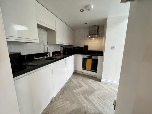 a kitchen with white cabinets and a wooden floor at The Coach House - with hot tub in St Austell
