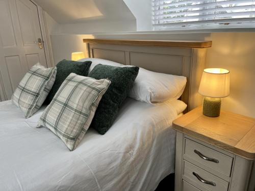 a bed with pillows and a lamp on a night stand at The Coach House - with hot tub in St Austell