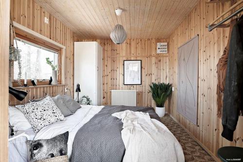 ein Schlafzimmer mit einem Bett in einer Holzwand in der Unterkunft Sjönära hus med grillstuga & vacker omgivning in Gråbo