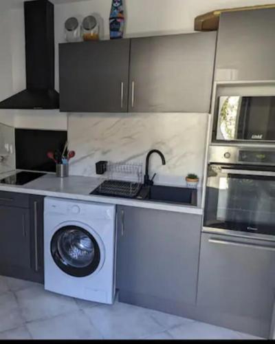 une cuisine avec un lave-linge et un micro-ondes dans l'établissement Partie de villa moderne avec acces piscine, à Villeneuve