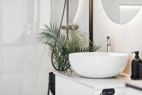 a bathroom with a white sink and a plant at Sjönära hus med grillstuga & vacker omgivning in Gråbo