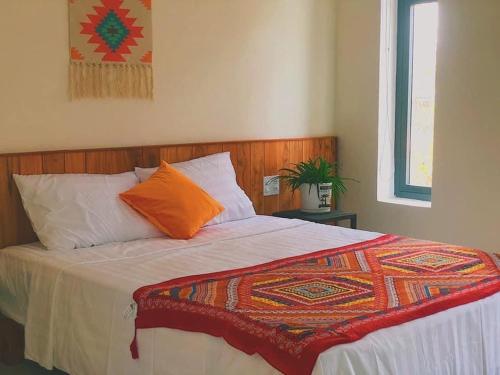 a bedroom with a large bed with an orange pillow at De Mai’s apartment in Hoi An