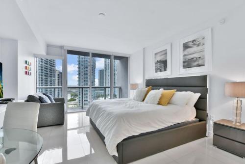 a white bedroom with a large bed and a desk at Studio at Icon Brickell Luxury Waterfront Building in Miami