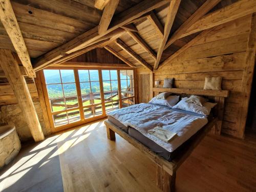 un letto in una camera in legno con una grande finestra di Berry a Klatovy