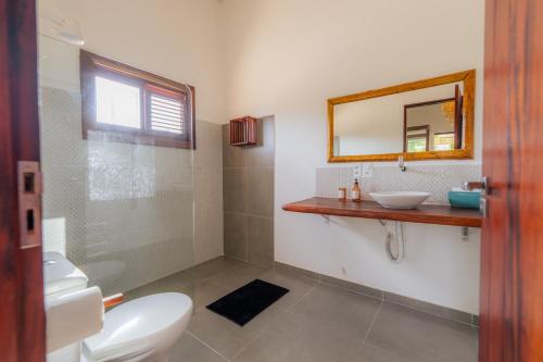 y baño con aseo, lavabo y espejo. en Villa Pousada 35knots Brasil, en Ponta do Anel