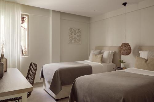 a bedroom with two beds and a table and a desk at Mare Paphos in Paphos