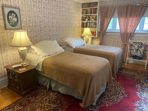 a bedroom with two beds and a book shelf at Bernard Gray Hall Bed and Breakfast in Niagara-on-the-Lake