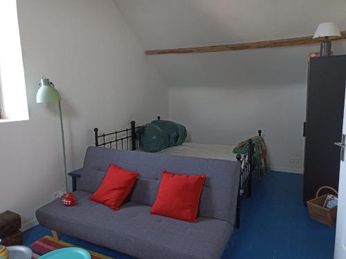 ein Wohnzimmer mit einem Sofa mit zwei roten Kissen in der Unterkunft Gite Meilhards in Meilhards