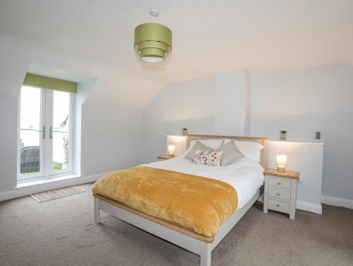 a white bedroom with a bed and a window at Glanrafon in Caernarfon