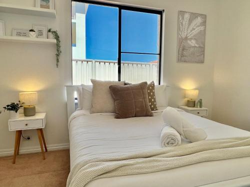 a bedroom with a white bed with a large window at Your Sunny Pool & Ocean Escape in Coogee