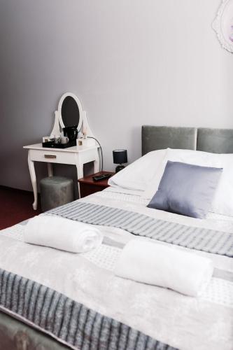 a bed with white sheets and a table with a mirror at Malibu in Brzeźnica