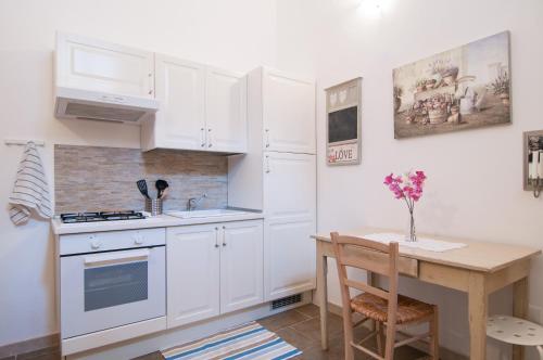 een keuken met witte kasten en een tafel met een vaas met bloemen bij Casa vacanze Cristina in Noto