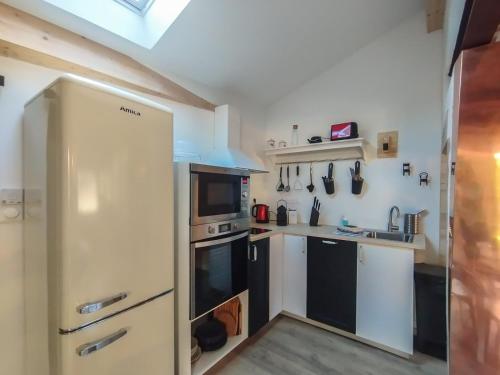 a kitchen with a white refrigerator and a microwave at LA VIGNE in Saulieu