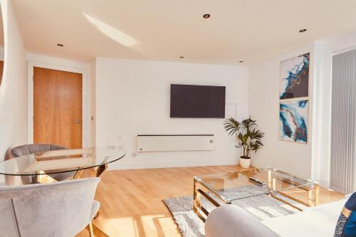 un soggiorno con tavolo e TV a parete di Modern Leeds Dock Apt &Free Secure Parking! a Leeds