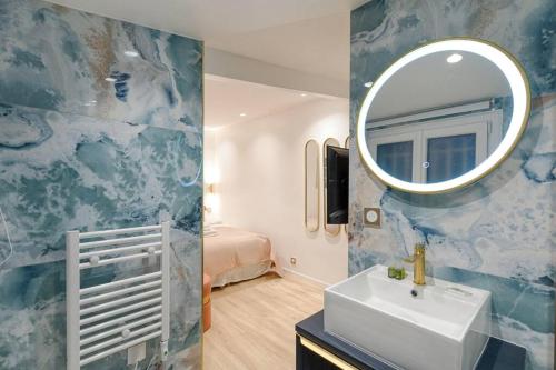 une salle de bain avec un lavabo et un miroir sur un mur dans l'établissement Coeur du Marais Arts&Metiers Magnifique Appartement, à Paris