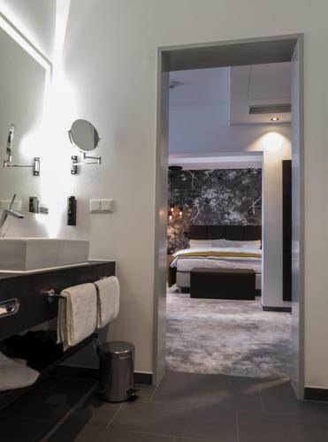 a bathroom with a bed and a sink and a mirror at Hotel Esplanade Dortmund in Dortmund