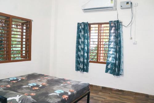 una camera con due finestre e un letto in esso di Satvik Stays a Puri