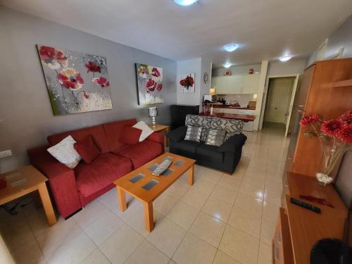 een woonkamer met een rode bank en een tafel bij Olivia Sunset 2 in Puerto de Santiago
