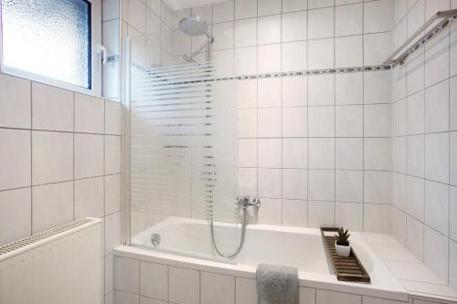 een wit betegelde badkamer met een douche en een bad bij Kirsten's Hike n Bike Ferienwohnung in Schmallenberg