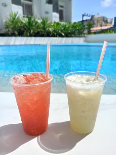 duas bebidas sentadas numa mesa ao lado de uma piscina em Gree Hotel em São Luís