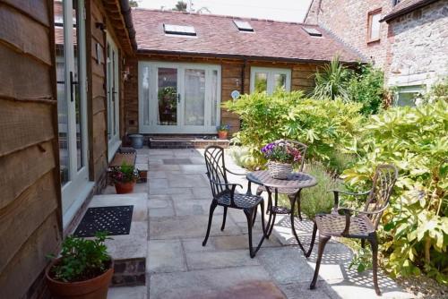 a patio with chairs and a table on a porch at Nest Holiday Hideaway Dove Cottage-Beautiful Location in the Long Mynd Area of Outstanding Natural Beauty-WHIRLPOOL JACUZZI BATHS!! in Picklescott