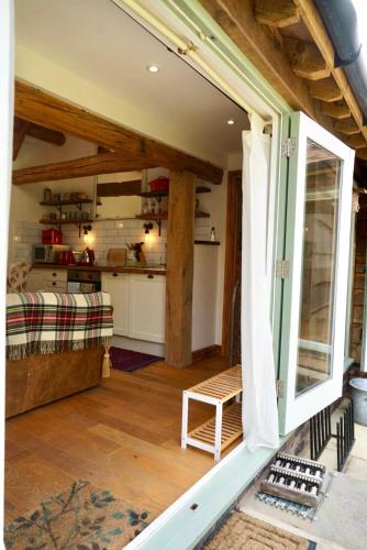 a living room with a large window and a kitchen at Nest Holiday Hideaway Dove Cottage-Beautiful Location in the Long Mynd Area of Outstanding Natural Beauty-WHIRLPOOL JACUZZI BATHS!! in Picklescott