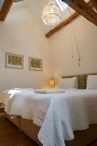 a bedroom with a large white bed with a chandelier at Nest Holiday Hideaway Dove Cottage-Beautiful Location in the Long Mynd Area of Outstanding Natural Beauty-WHIRLPOOL JACUZZI BATHS!! in Picklescott