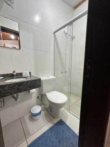 a bathroom with a toilet and a glass shower at Nascer Do Sol Suites in Guarda do Embaú