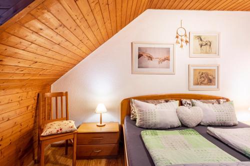 a attic bedroom with two beds and a chair at Landhaus Am Schmiedebach in Wittenschwand